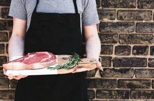 man holding steak and cutting board